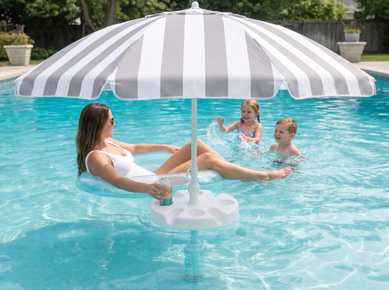 A mother in the shade of a FloatMate with a drink from its table while two children play in the pool